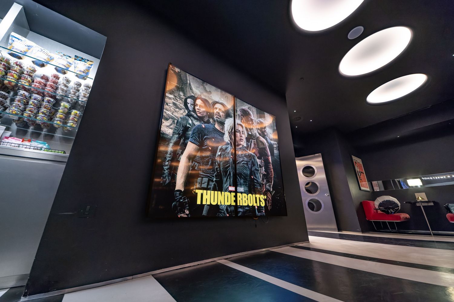 TrouDigital large-format digital screen displaying a movie poster in a cinema foyer with concession stand, digital signage product photography