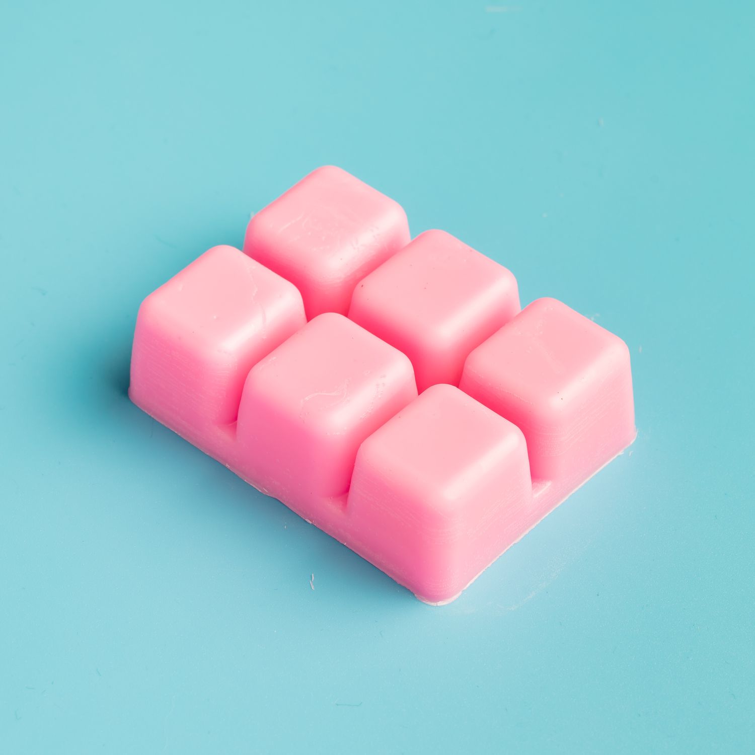 Pink wax melt snap bar on a turquoise background, handmade home fragrance product photography Southampton