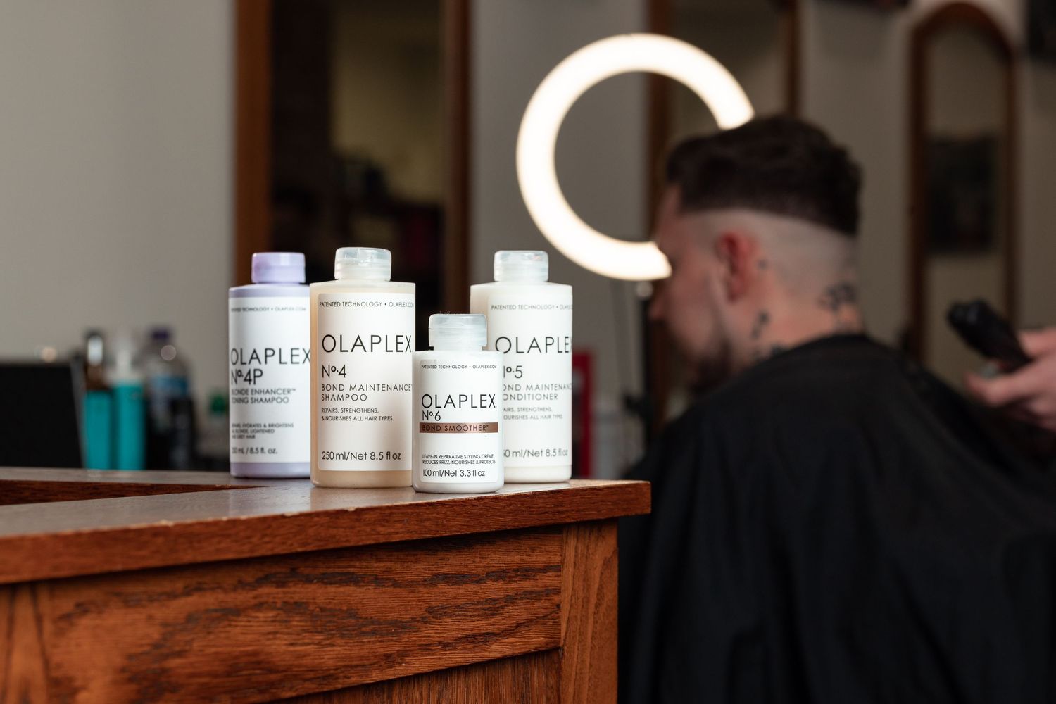 Olaplex haircare bottles including shampoo, conditioner and bond smoother on a wooden counter at Above Barbers salon, product photography Southampton