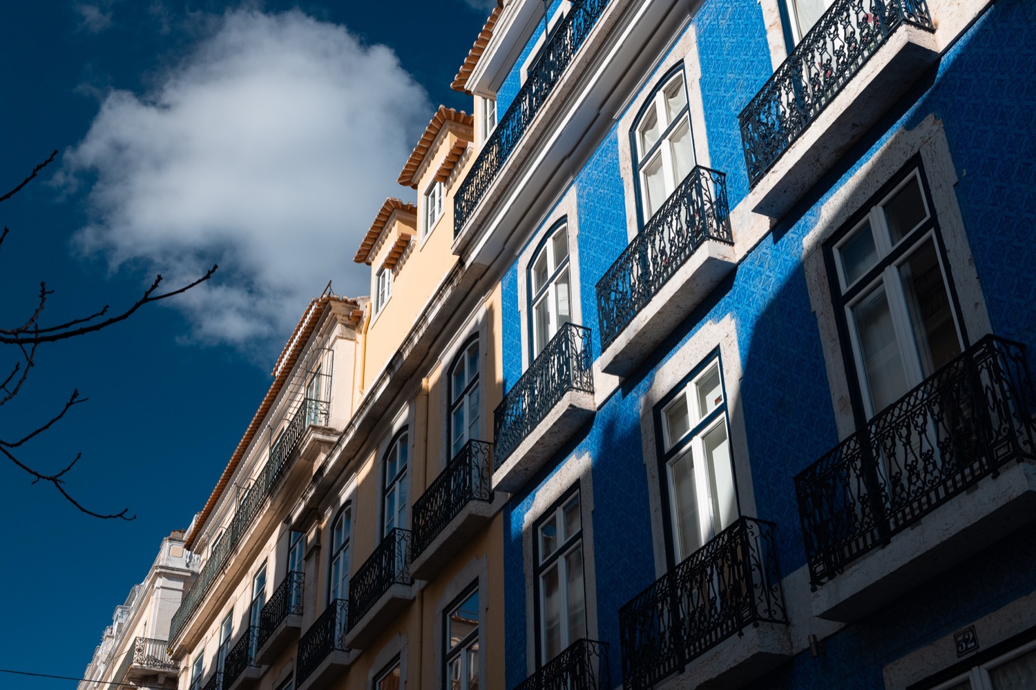 Blue and white azulejo facades with wrought-iron balconies against a bright sky, Lisbon, Portugal, travel photography
