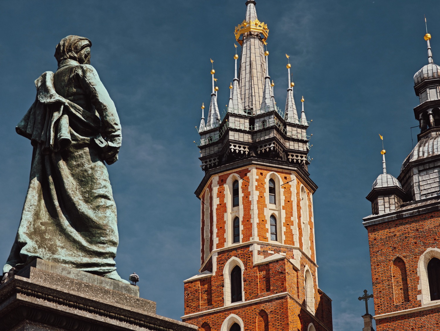 Bronze monument in front of brick gothic basilica spires, Krakow, Poland, travel photography