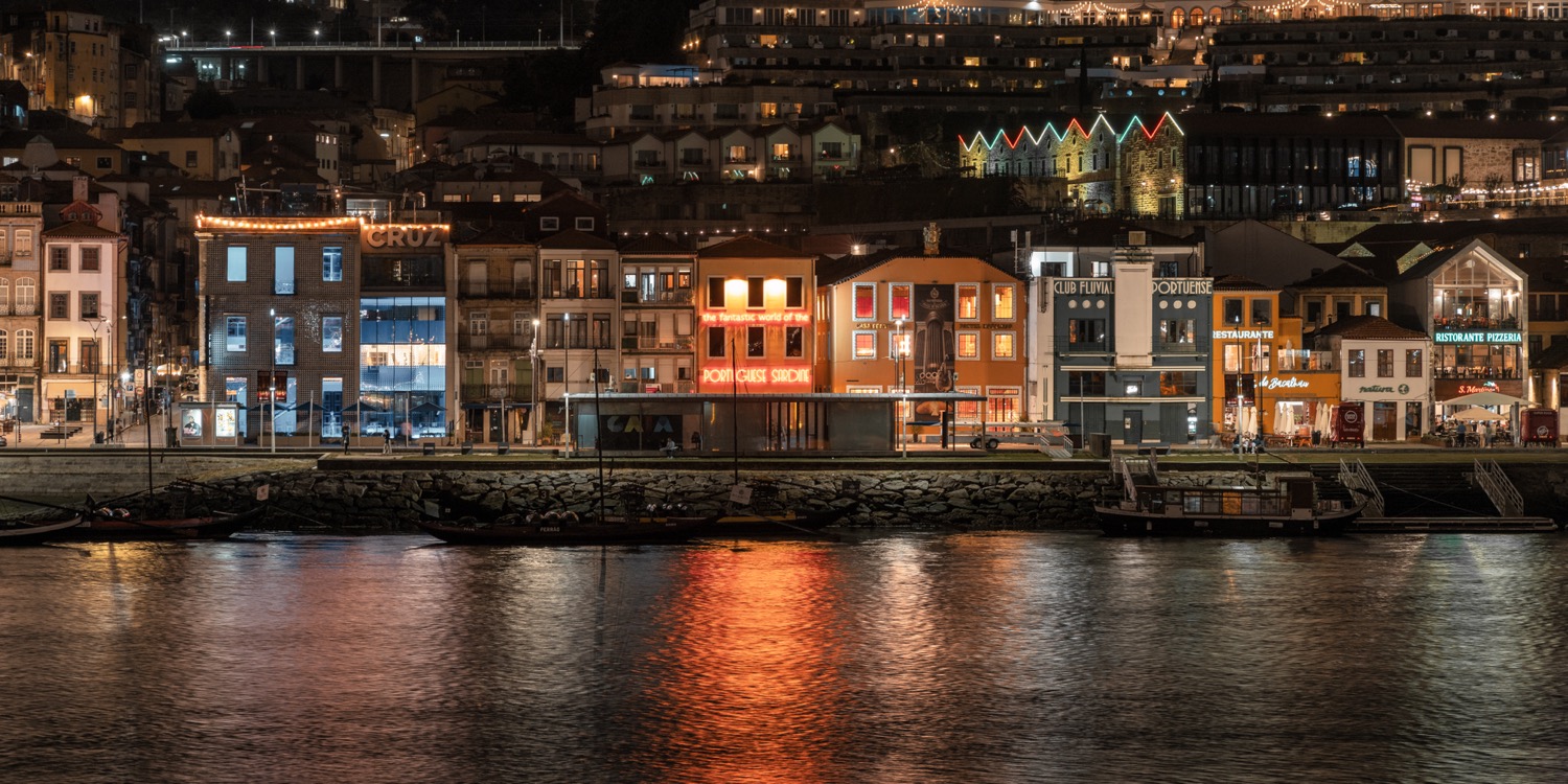 The Cais da Ribeira waterfront at night, lit facades reflected in the Douro, Porto, Portugal, travel photography