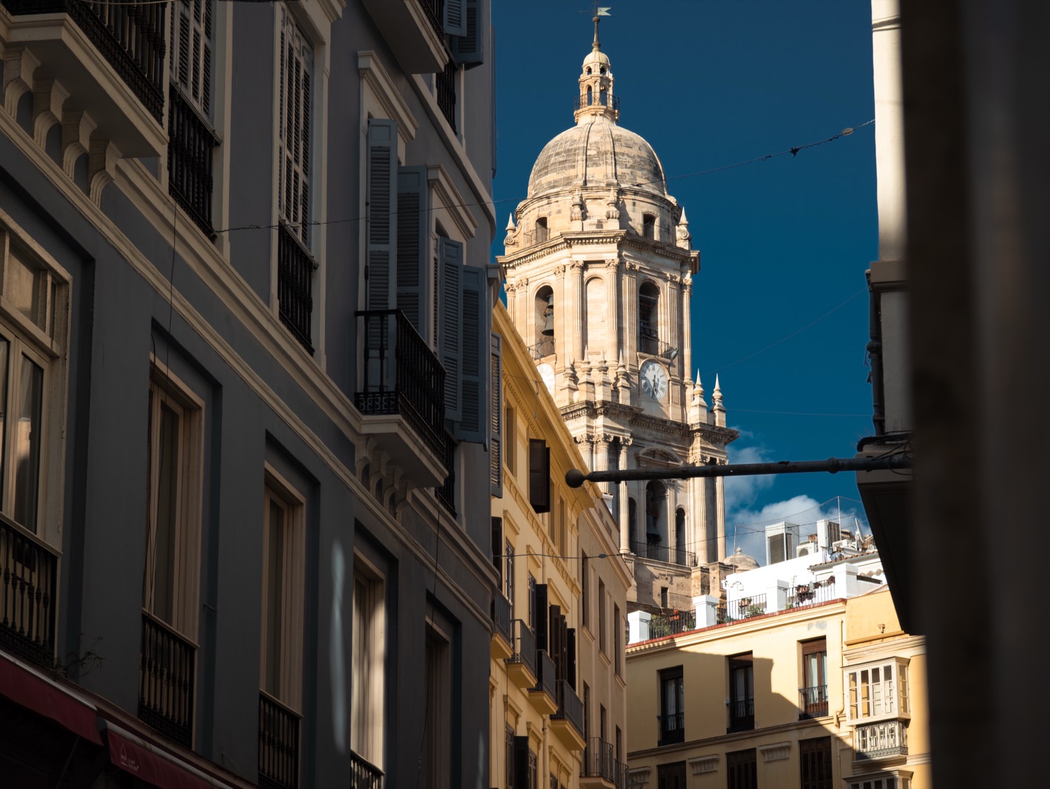 Malaga cathedral tower framed between the walls of a narrow street, Spain, travel photography