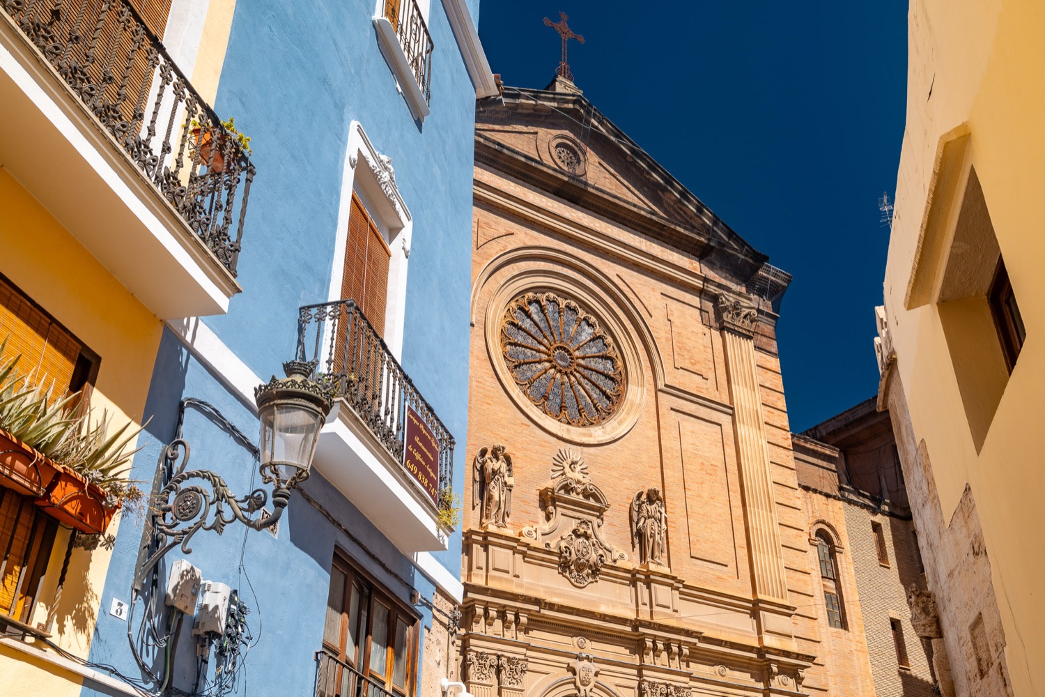 Church rose window beside blue and ochre facades, Valencia, Spain, travel photography