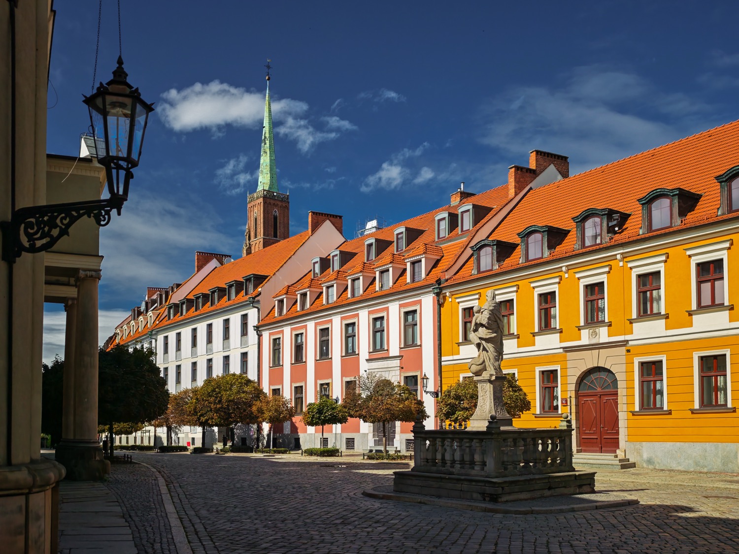 Cobbled street with a stone statue and yellow and white townhouses, Wroclaw, Poland, travel photography