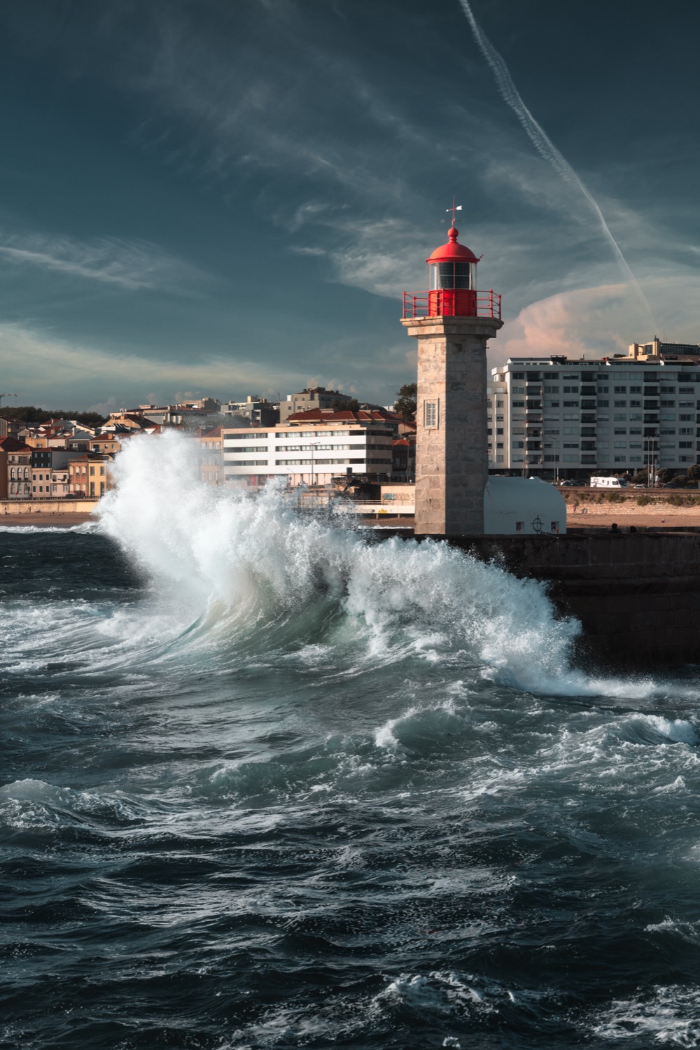 Felgueiras lighthouse with a wave breaking hard against the breakwater, Foz do Douro, Porto, Portugal, travel photography