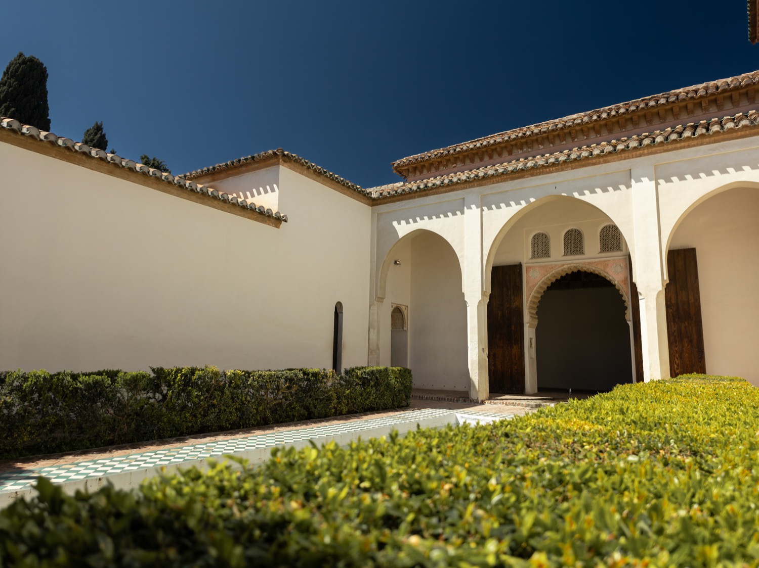 Moorish courtyard with white arches, clipped hedges and a tiled roof, Andalusia, Spain, travel photography