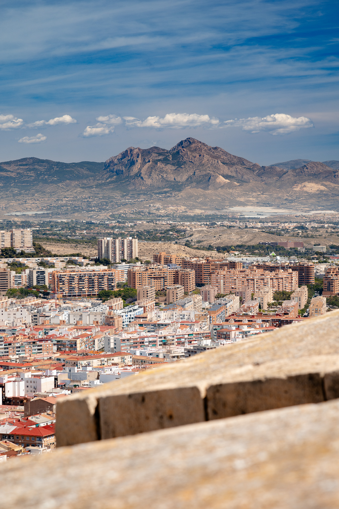 City rooftops below the mountains, seen over the stone battlements of the castle, Alicante, Spain, travel photography