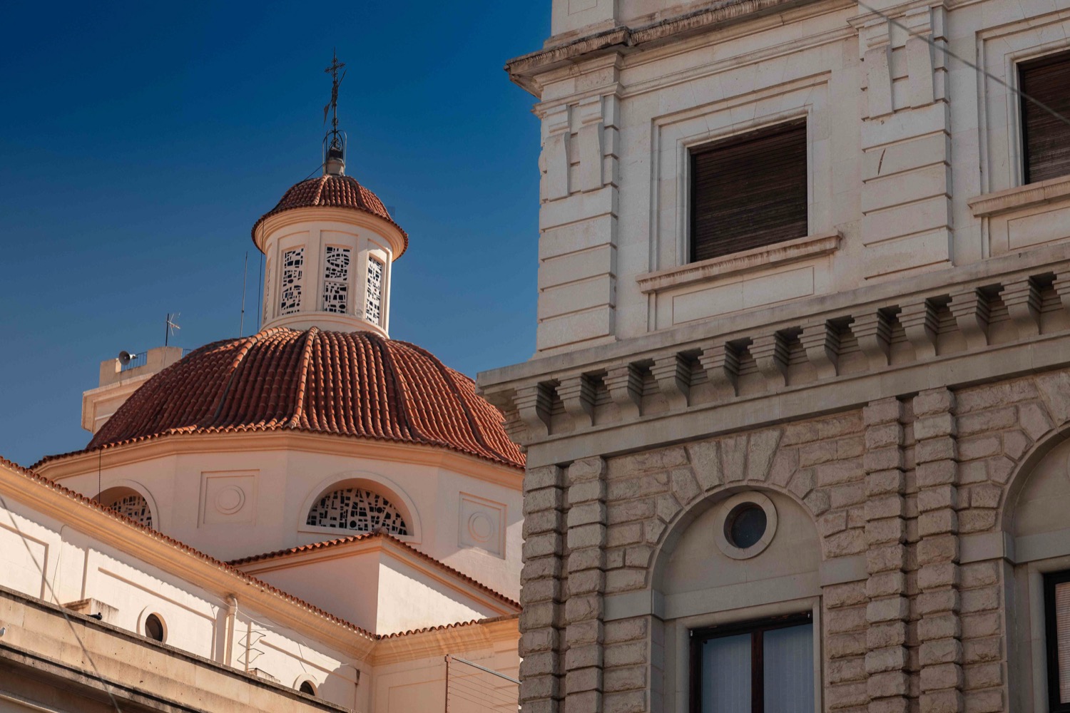Tiled church dome beside a classical stone facade against a deep blue sky, Alicante, Spain, travel photography