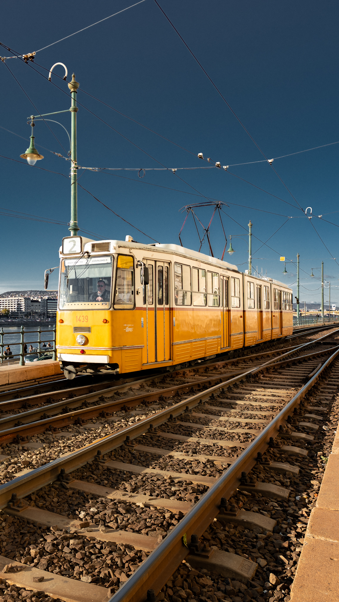 Yellow tram waiting on the tracks beneath overhead wires, Budapest, Hungary, travel photography