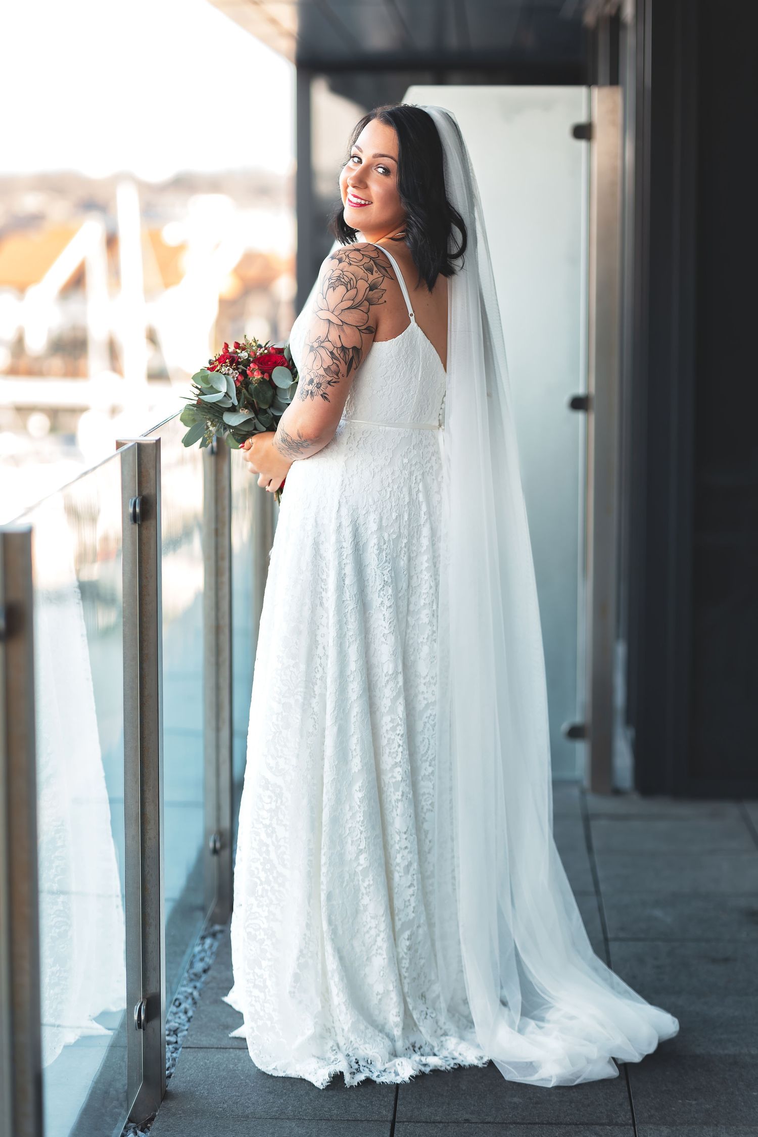 Tattooed bride in white lace dress and veil standing on a balcony with harbour views at the Harbour Hotel Southampton, bridal portrait photography