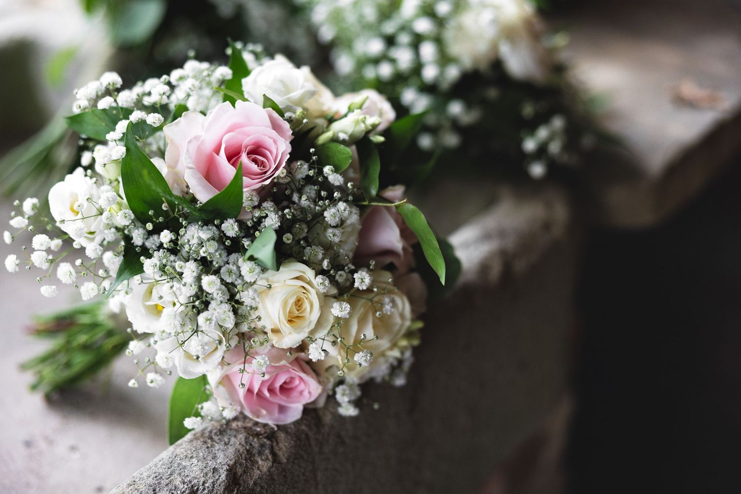 Close-up of bridal bouquet with pink roses, white flowers and baby's breath on a stone surface, wedding detail photography Southampton