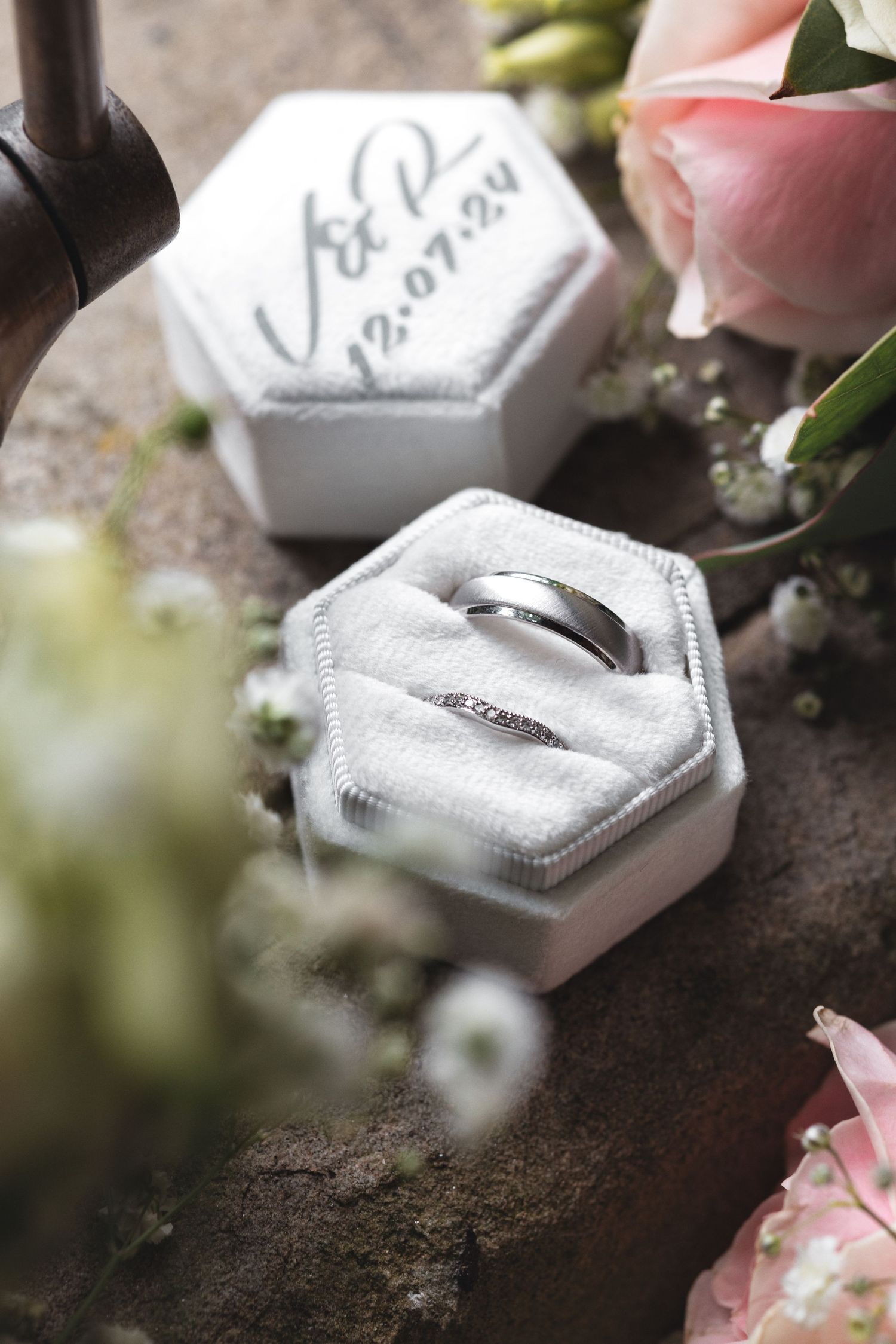 Wedding rings in a white hexagonal ring box with personalised date lid surrounded by baby\