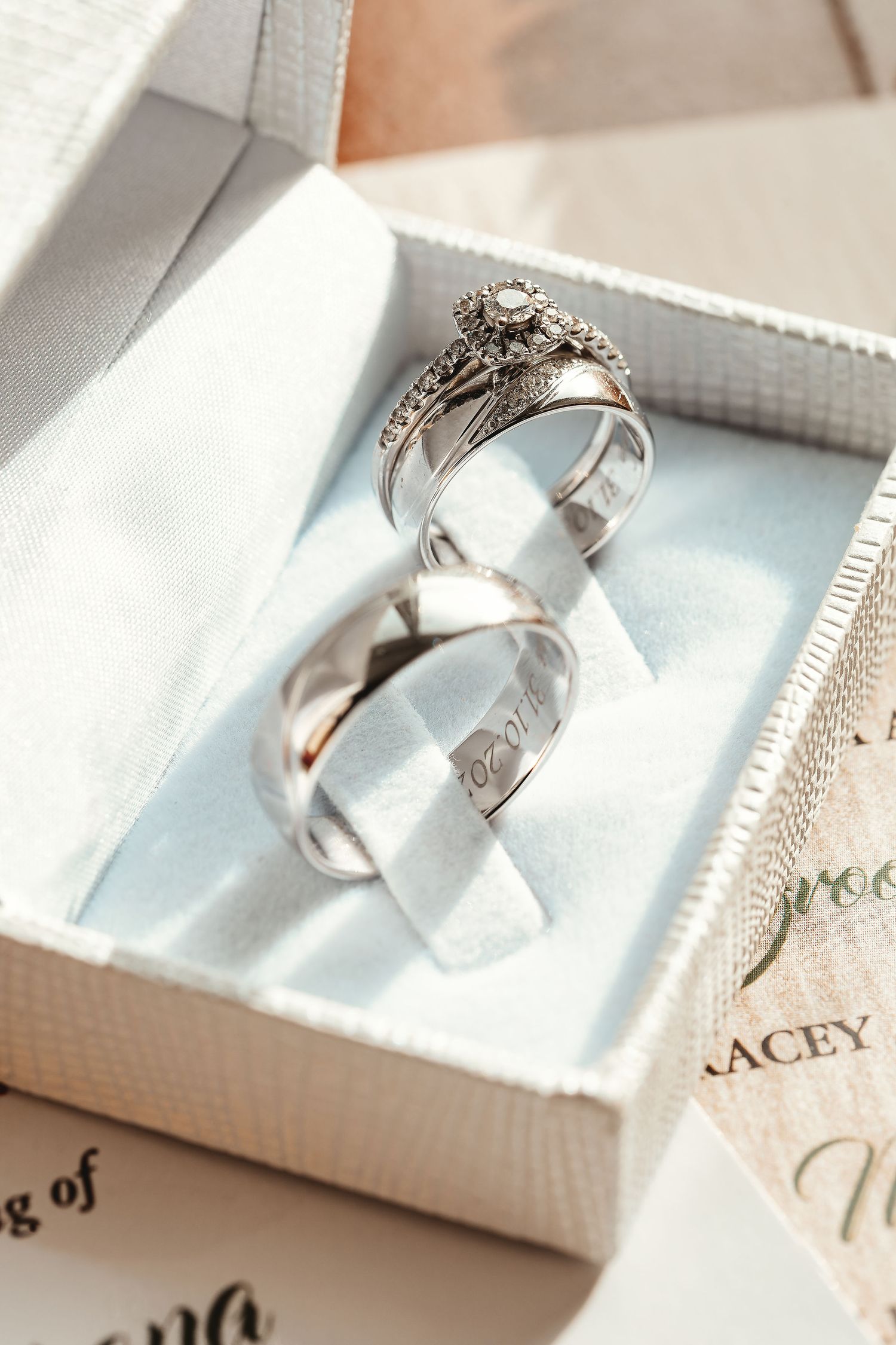 Close-up of wedding rings in a white ring box with engraved date alongside wedding stationery, wedding detail photography St Audrie\