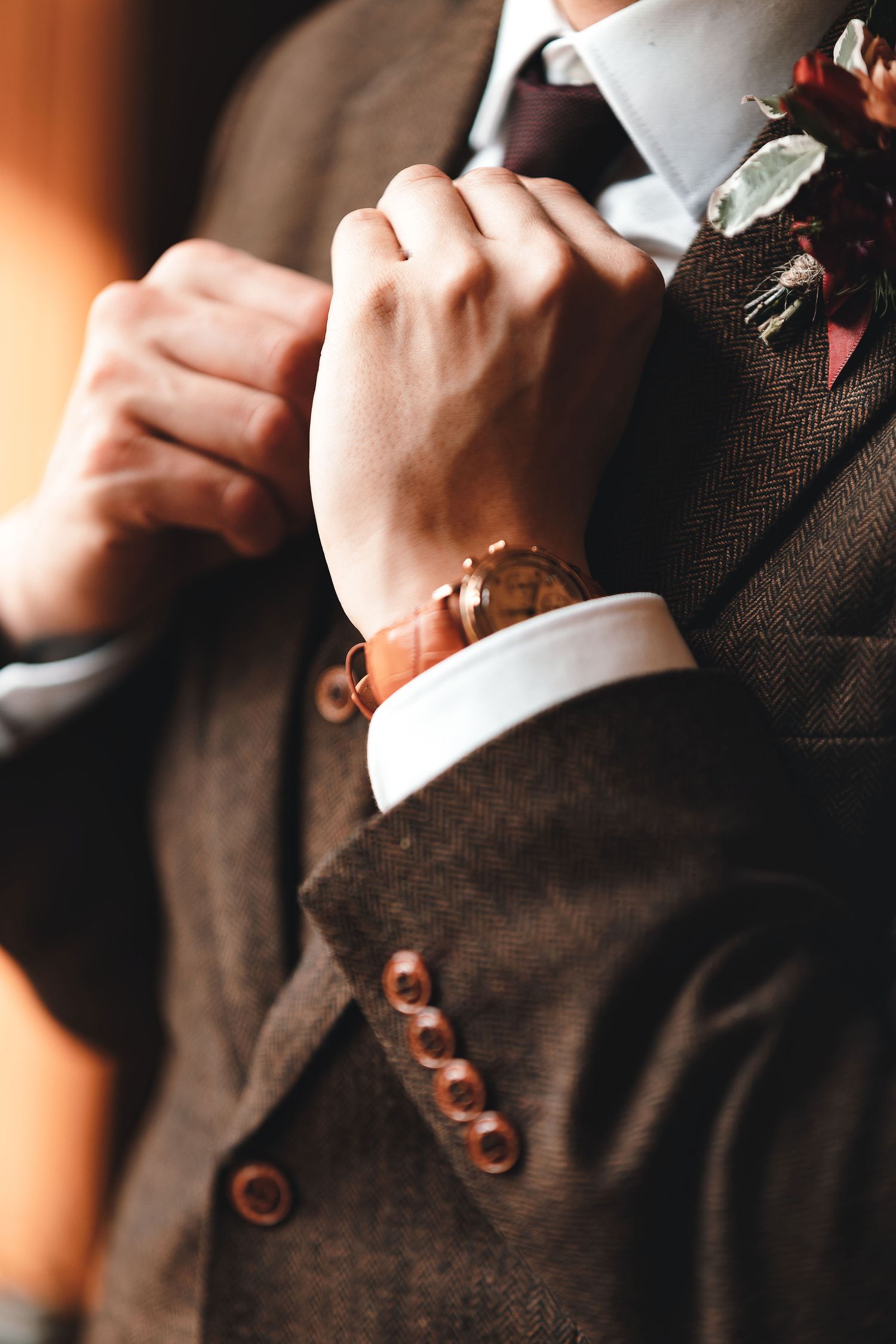 Close-up of groom adjusting cuffs showing tweed suit and boutonniere, wedding detail photography St Audrie\